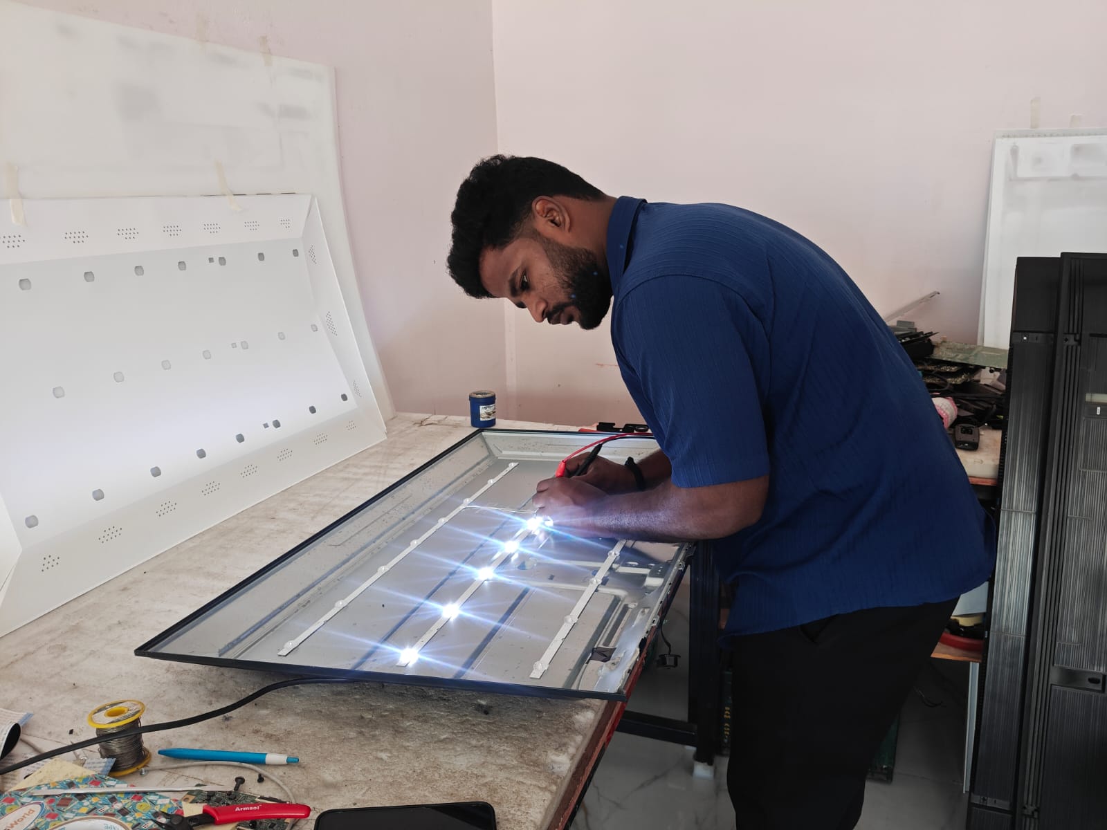 Technician repairing LED TV backlight at customer's home in Hyderabad